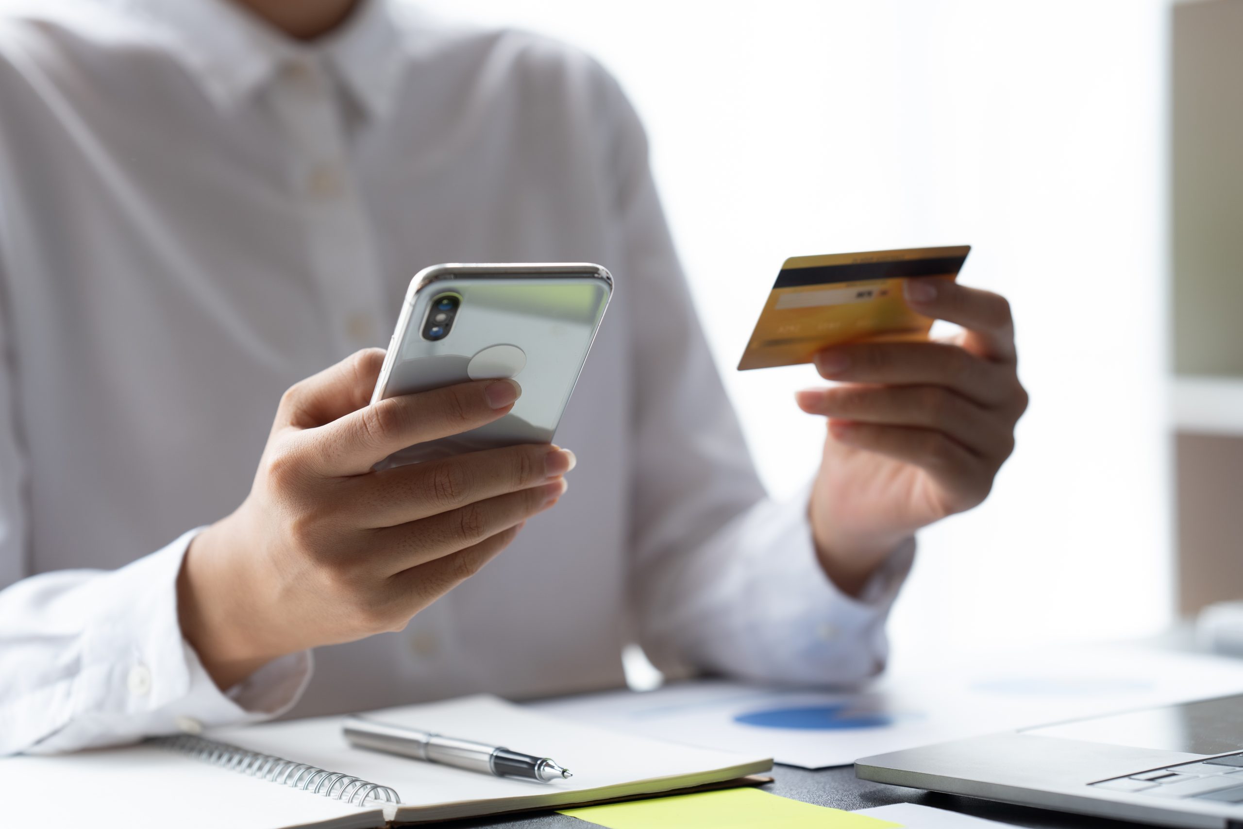 A man is holding a credit card while sitting at a desk.