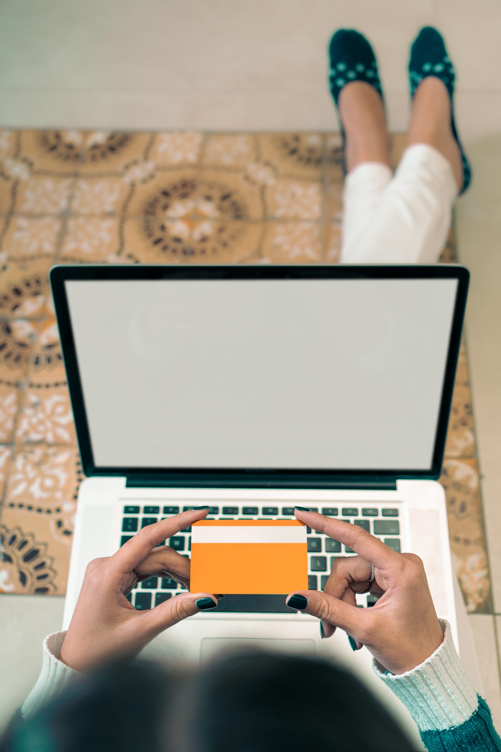 A woman is using a laptop with a credit card.